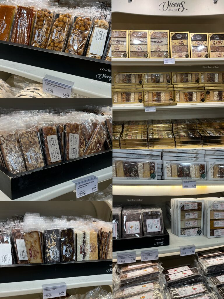 スペイン・マドリードのVicens（ビセンス）店内に並ぶ個包装タイプのトゥロン。アーモンドヌガーやチョコレート、ハード・ソフトタイプなど多彩なフレーバーが揃うスペイン伝統菓子。人気の定番土産。1個2.95€から買える。