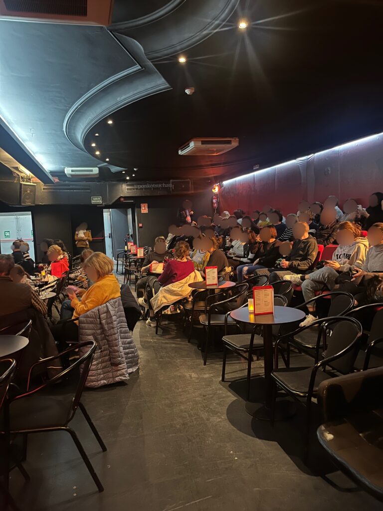 テアトロ・フラメンコ・マドリードの客席エリア。円卓と椅子が並ぶカジュアルなタブラオ形式で、観客が続々と着席している開演前の様子。観客層の年齢や雰囲気がわかる座席後方の写真。