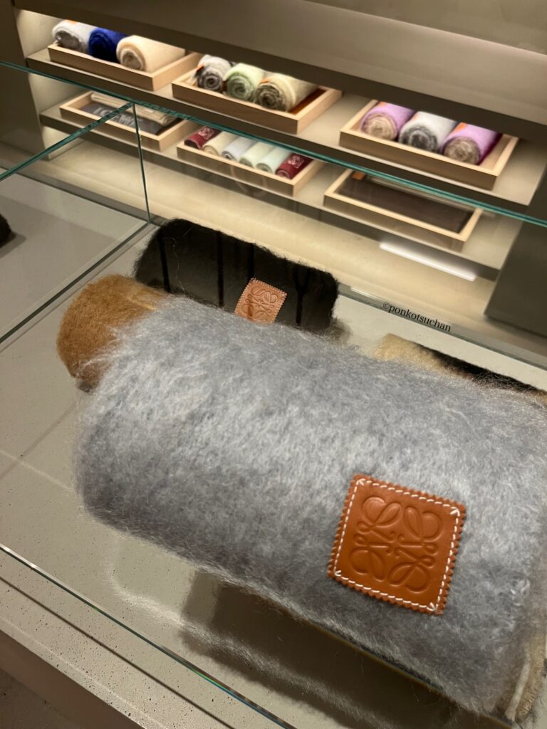 ロエベのマフラーとストールが並ぶショーケース。カラーバリエーションと素材感が分かる展示。