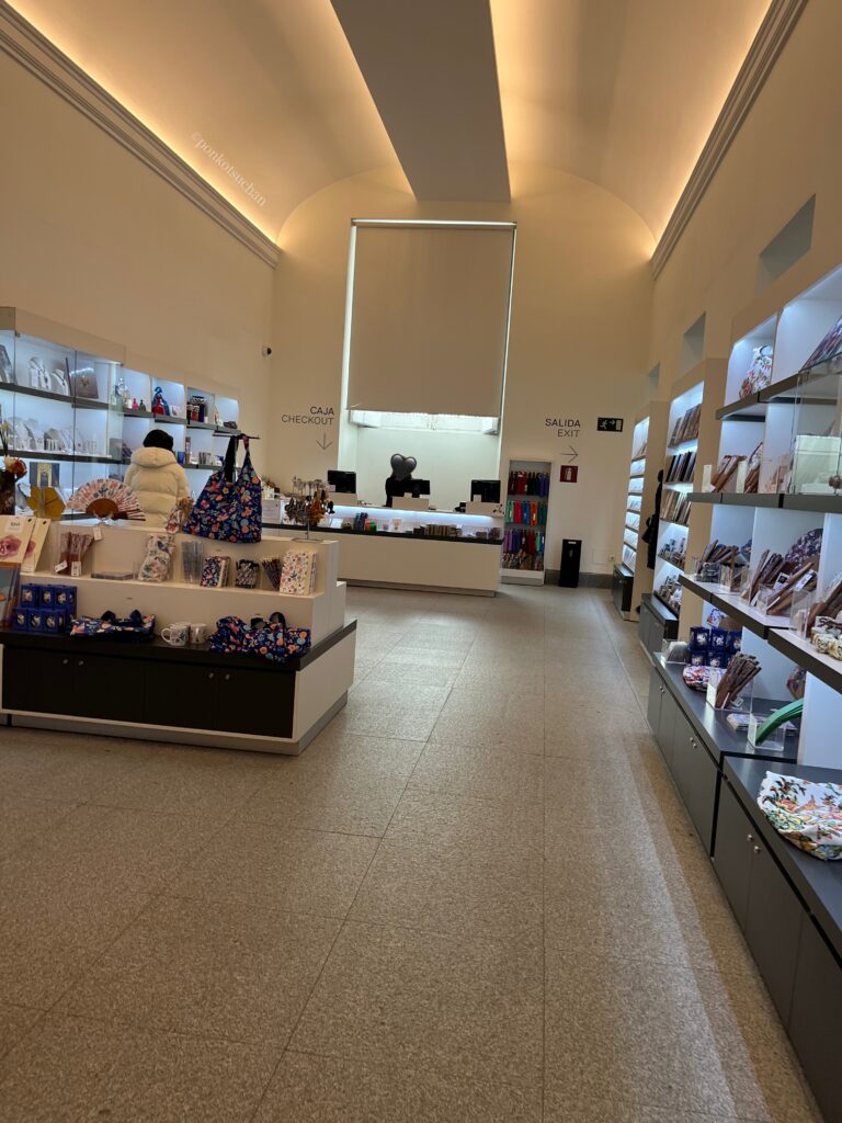 マドリード王宮の公式ショップ内部の様子。広々とした店内にお土産や雑貨が並び、レジカウンターと出口案内が見える。